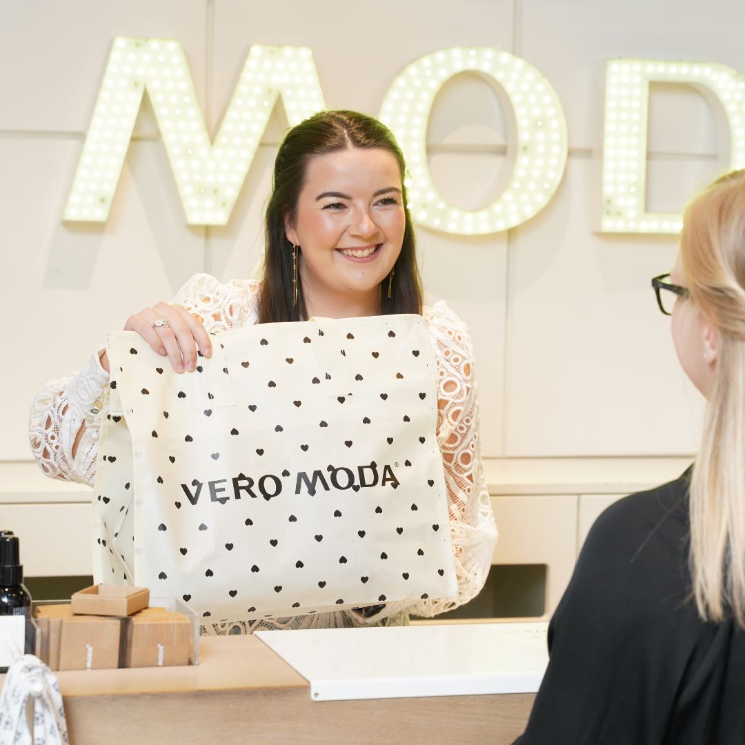 Medarbejder fra Vero Moda i Randers giver kunde en pose med købt tøj. 
